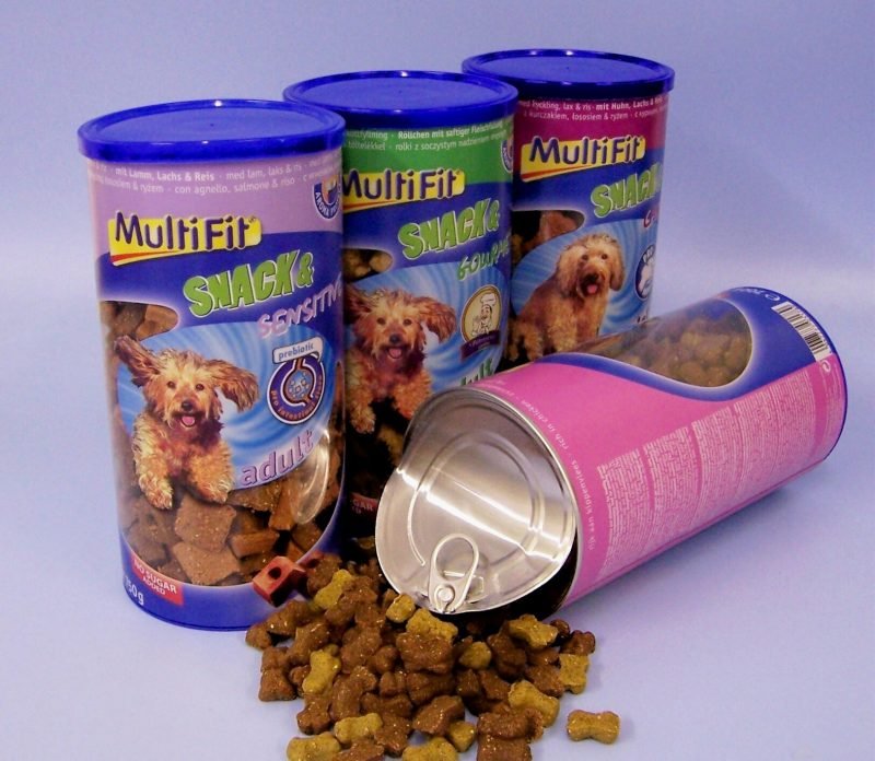 4 large coloured packaging tins of dry dog food,. One tin spilled out.